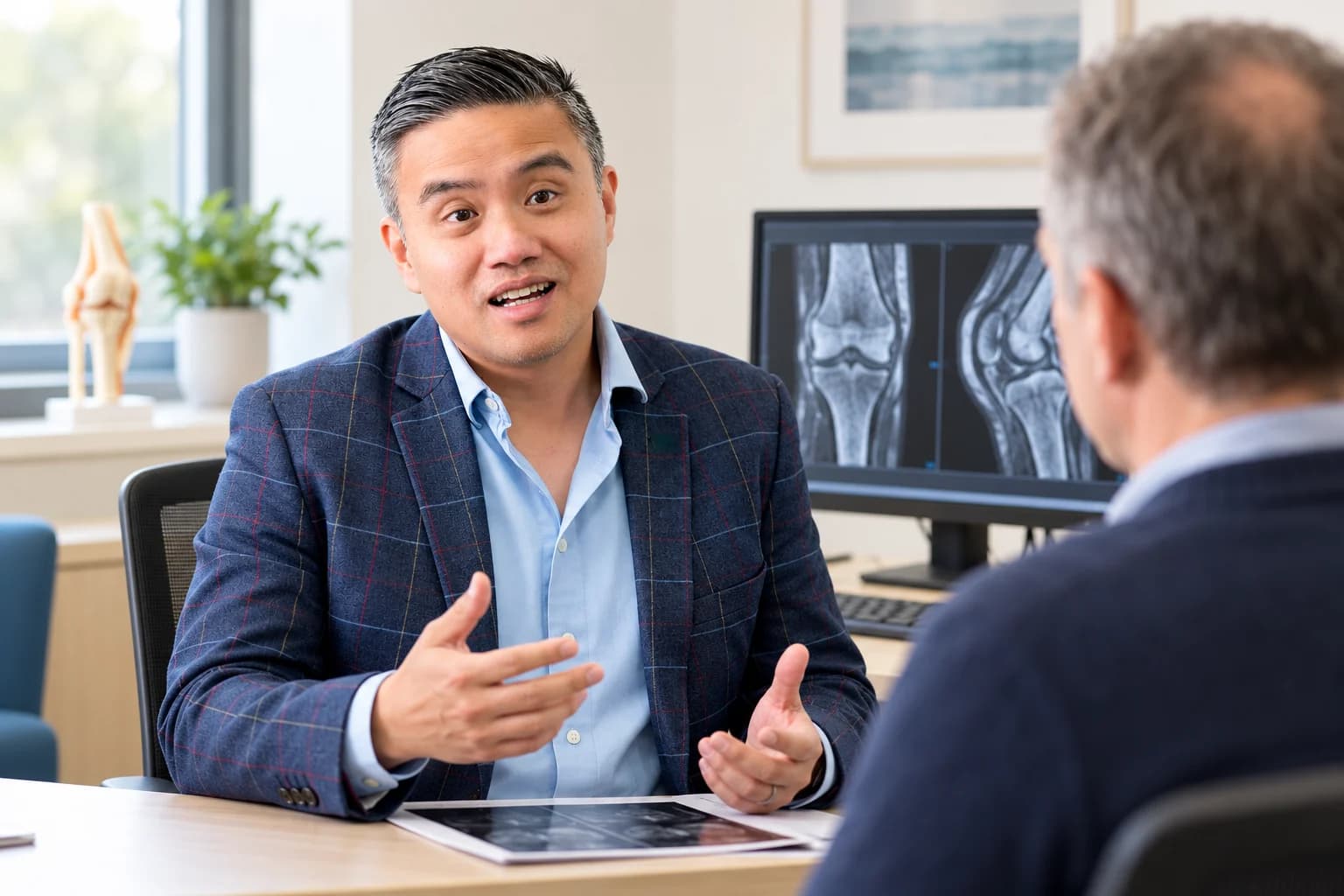 A clinician and patient discussing knee images during a consultation